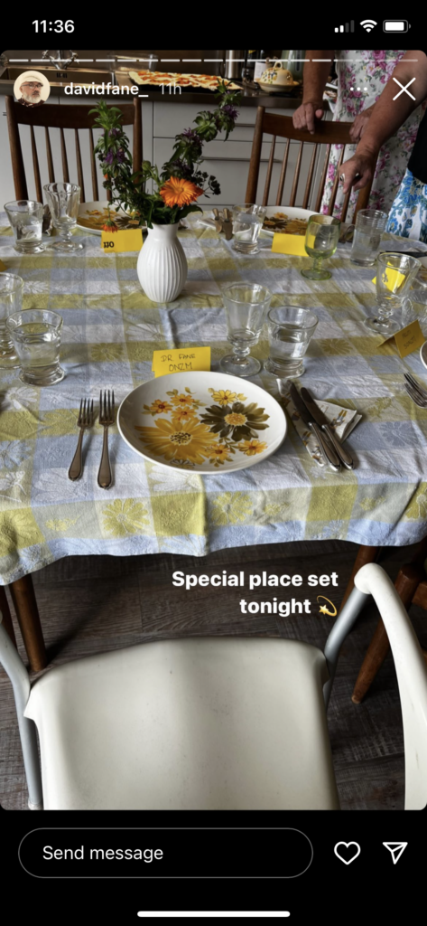 A small dinner table. Yellow cards denote who sits where. The card directly in front reads: "Dr. Fane ONZM". Text reads: "Special place set tonight"