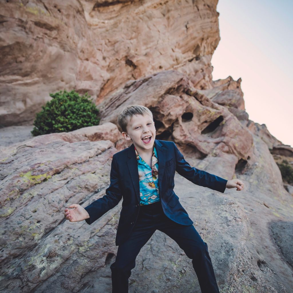 Young Theo Darby gives a silly smile atop some high desert rocks