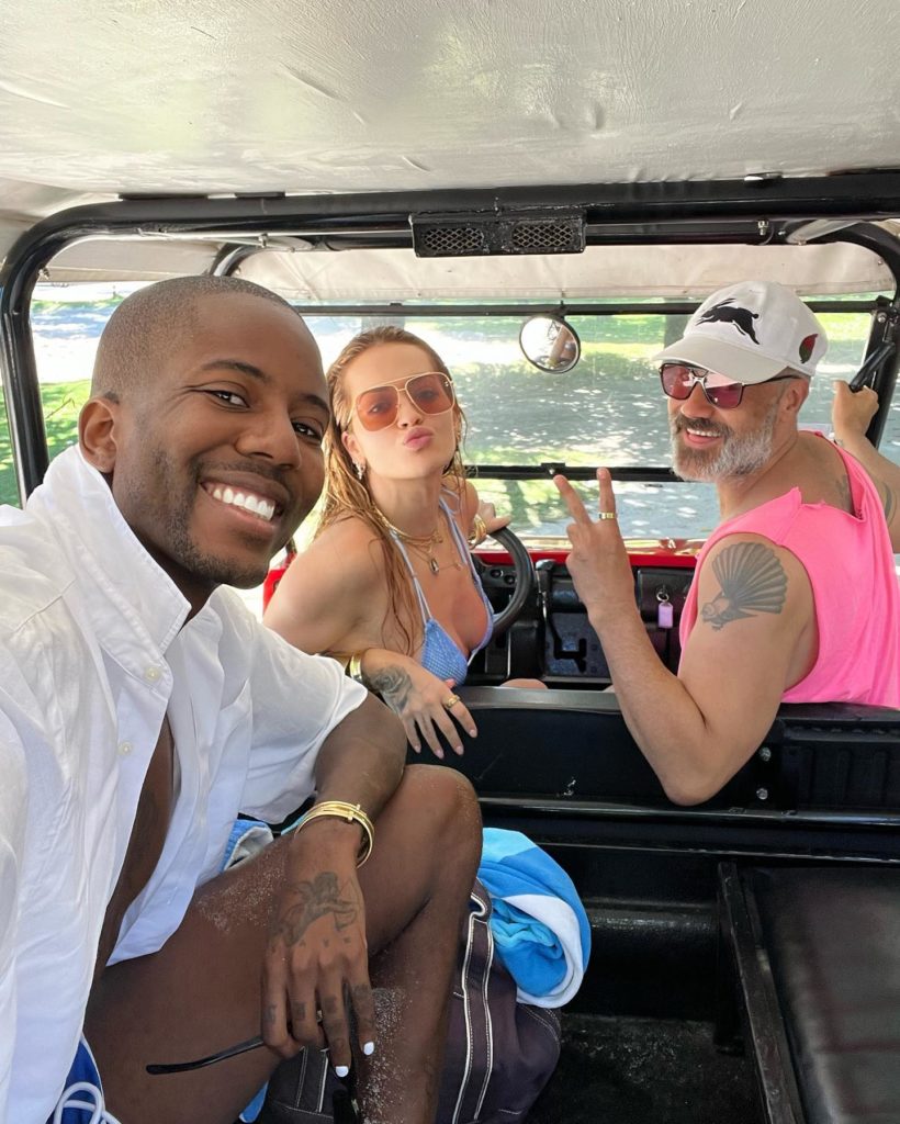 Vas J. takes a selfie in what looks to be a golf cart or small vehicle with Rita and Taika in the front seat.