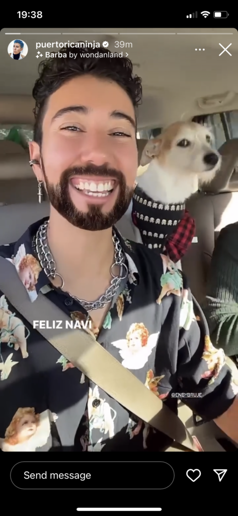 1st of 2-part screenshot of a video I can't find now. Vico smiles from the driver's seat. Their small dog looks on from the back seat. "Feliz Navi..." is beginning to appear on-screen.