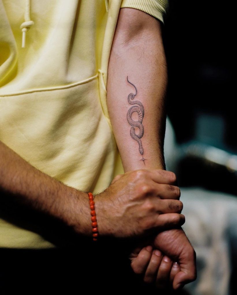 Taika shows off his new ink on his left forearm, a curly snake with its head pointed towards a shining star.