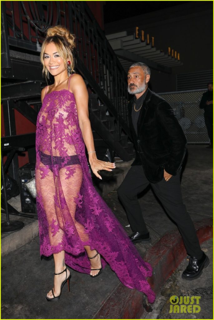 Rita Ora and Taika Waititi arrive at the pre-Golden Globes party. Rita is wearing a see-through pink dress, Taika a black velvet suit.