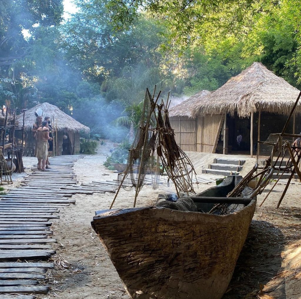 Behind the scenes from S1. The set of the Native islanders' village. A wood plank walkway leads to some thatched-roof huts.