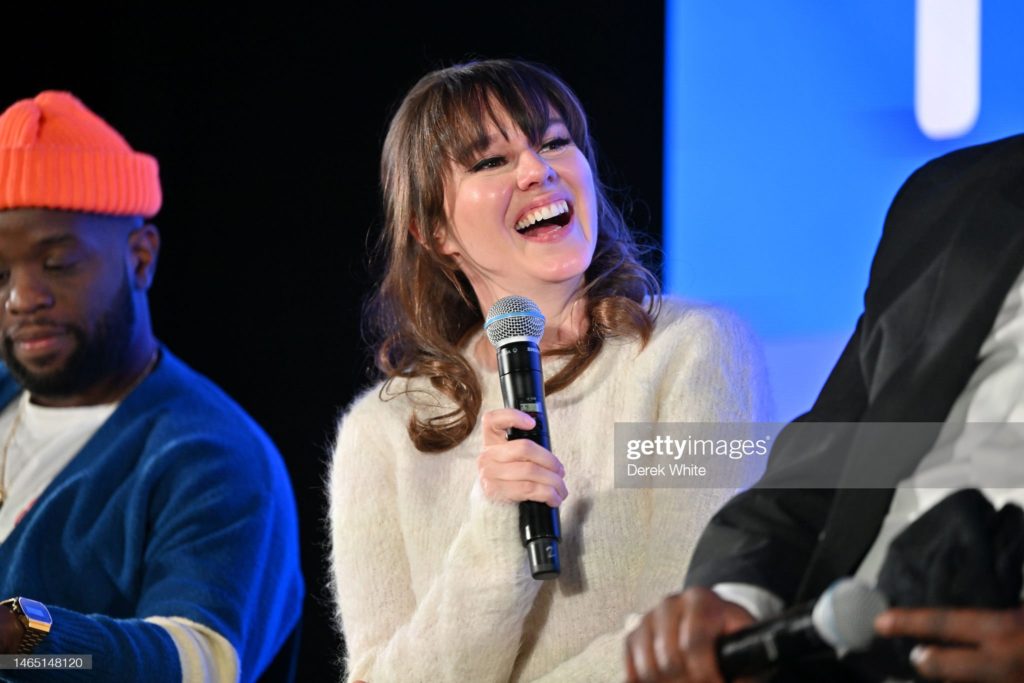 SCAD TVFest 2023. Claudia has a mic in hand, laughing at a question during a panel session with fellow "Killing It" cast.