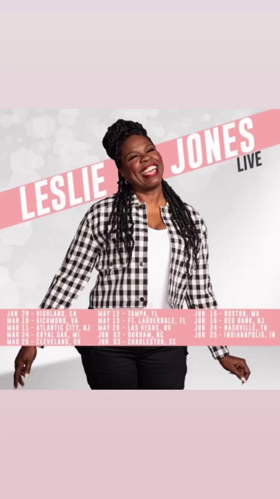 Leslie Jones poses, laughing, in front of a gray stylized background. Superimposed is a pink bar with dates and cities listed.