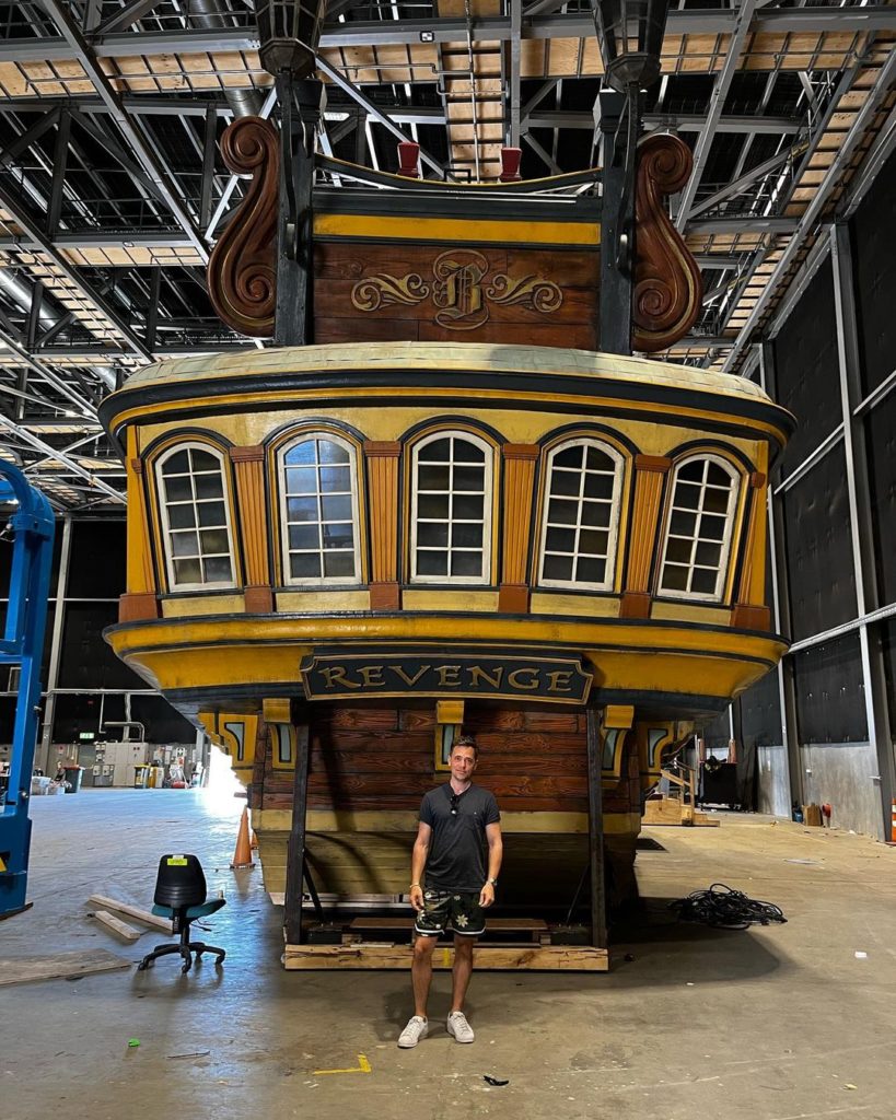 A full picture of The Revenge, in a production studio. David is standing in the same spot, and looks very small compared to the ship.