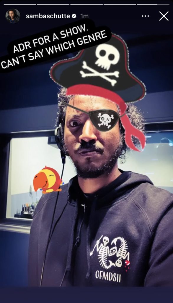Samba stands with his season 2 hoodie, and a pirate hat and eyepatch emojis (?) added to his face. Text reads: “ADR for a show. Can’t say which genre.”